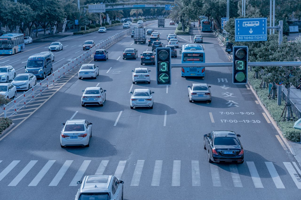 Wide shot of urban traffic at a busy city intersection with cars and buses.